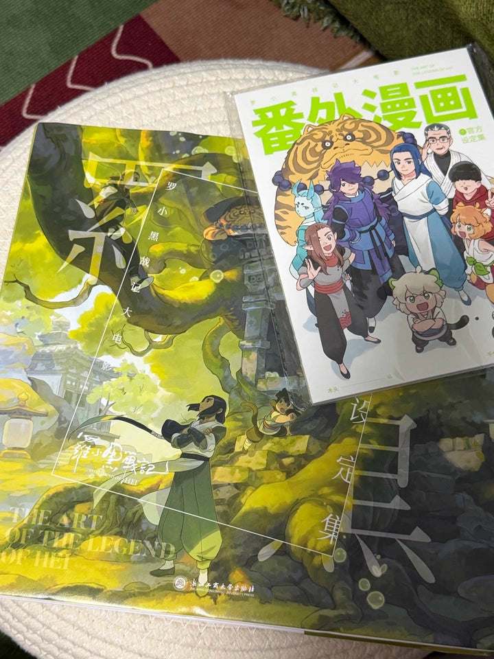 The Legend of Hei movie art setting book and comic booklet on a blue sweater