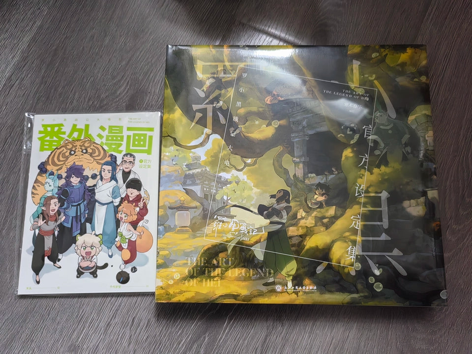 The Legend of Hei movie art setting book with companion comic booklet on a wooden table